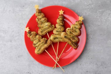 Noel ağacı şekilli abur cuburlar puf böreğiyle yapılır, pesto sosu ve peynir gri masada, üst manzara