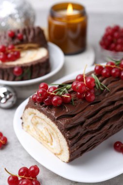 Lezzetli Noel kütüğü (geleneksel Noel pastası) gri masa üzerinde kırmızı frenk üzümü, yakın plan