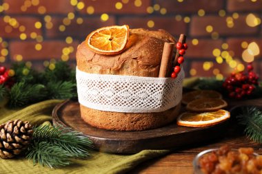 Noel yemeği. Lezzetli Panettone pastası, malzemeler ve ahşap masanın üzerindeki dekoratif dekor arka planda bulanık ışıklar, yakın plan. Bokeh etkisi