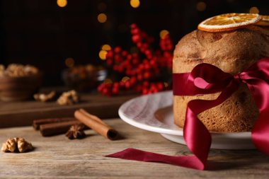 Noel yemeği. Lezzetli Panettone pastası, malzemeler ve ahşap masa üzerindeki şenlikli dekor arka planda bulanık ışıklar, yazı için yer. Bokeh etkisi