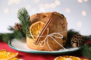 Noel yemeği. Lezzetli Panettone pastası, baharatlar ve arka planda arka planda bulanık ışıklarla süslü bir dekor, yakın plan. Bokeh etkisi