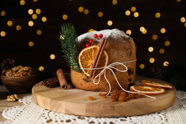 Noel yemeği. Lezzetli Panettone pastası, malzemeler ve ahşap masanın üzerindeki dekoratif dekor arka planda bulanık ışıklar, yakın plan. Bokeh etkisi