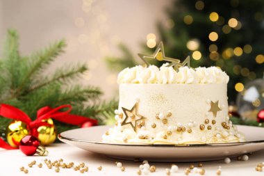 Bulanık ışıklara karşı beyaz masanın üzerinde Noel süsü olan enfes bir pasta.