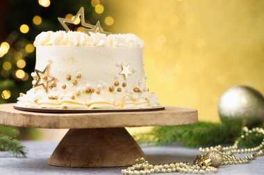 Gri masadaki Noel desenli lezzetli pasta altın arka planda bulanık ışıklar, yakın plan