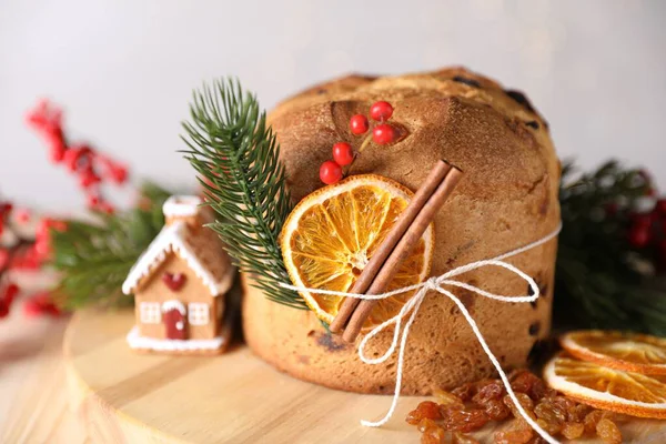 Noel yemeği. Lezzetli Panettone pastası, malzemeler, zencefilli kek evi ve arka planda bulanık ışıklı şenlikli dekorasyon, yakın plan. Bokeh etkisi