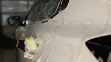 Oto yıkayan adam araba yıkamada süngerle yıkıyor.