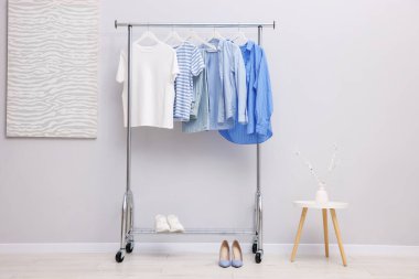 Askıda asılı farklı şık kıyafetler ve açık duvarın yanında ayakkabı.