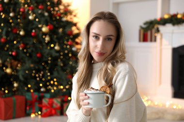 Güzel bir kadın krem şantili, tarçınlı ve portakal dilimli sıcak kakao içiyor. Mesaj için yer var. Noel sezonu