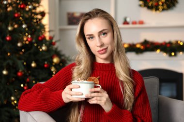 Güzel bir kadın krem şantili, tarçınlı ve portakal dilimli sıcak kakao içiyor. Noel sezonu