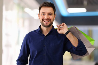 Alışveriş merkezinde torbaları olan mutlu bir adam.