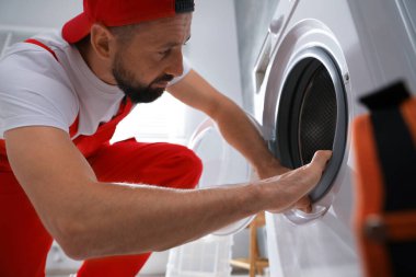 Profesyonel tamirci içeride bozuk çamaşır makinesini tamir ediyor.