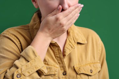 Yeşil arka planda bulantı çeken genç bir kadın, yakın plan.