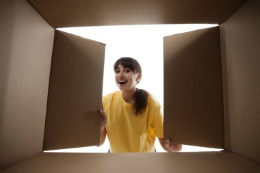 Kadın beyaz arka planda karton kutuya bakıyor, içeriden görüntüle