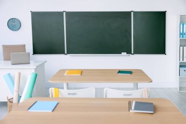 Sınıfta yeşil karatahta, masalar ve sandalyeler var. Tasarım için model