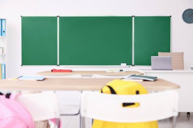 Sınıfta yeşil karatahta, masalar ve sandalyeler var. Tasarım için model