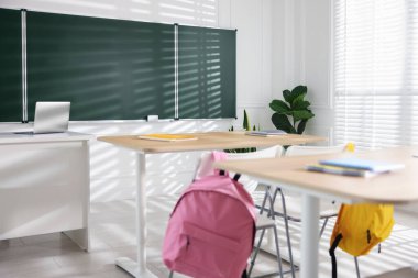 Sınıfta yeşil karatahta, sıralar ve sandalyeler.