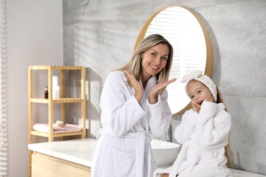 Banyoda bornozlu mutlu anne ve kız. Metin için boşluk