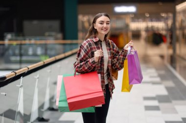 Alışveriş merkezinde farklı çantaları olan bir kadın.