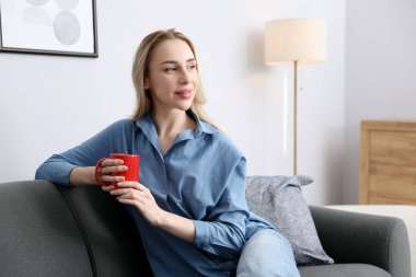 Evdeki kanepede bir fincan kakao içen kadın. Metin için boşluk