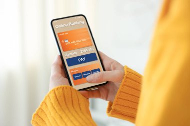 Çevrimiçi ödeme. Bankacılık uygulamasını kapalı mekanda akıllı telefonda kullanan bir kadın.