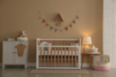 Bebek odasındaki beşik, masa, şifonyer, lamba ve dekorun bulanık görüntüsü