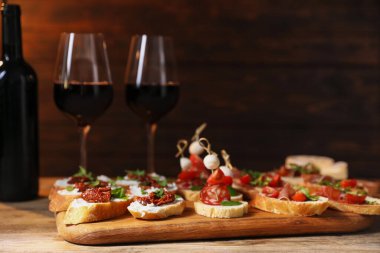 Farklı lezzetli bruschetalar ve ahşap masada kırmızı şarap.