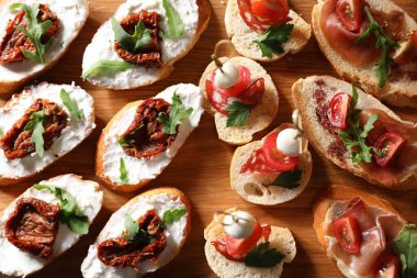 Farklı lezzetli bruschettalar ahşap masada, düz yatıyordu.