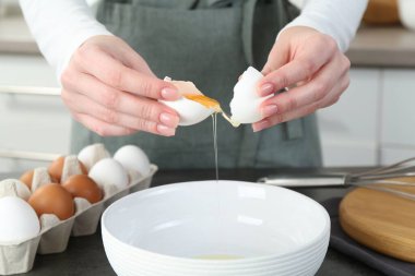 Mutfaktaki gri masada yumurta kıran kadın, yakın plan.