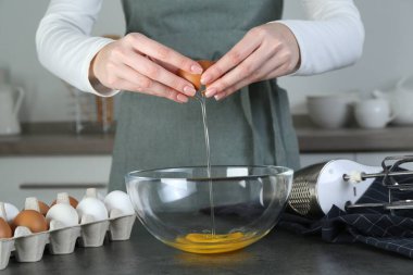 Mutfaktaki gri masada yumurta kıran kadın, yakın plan.