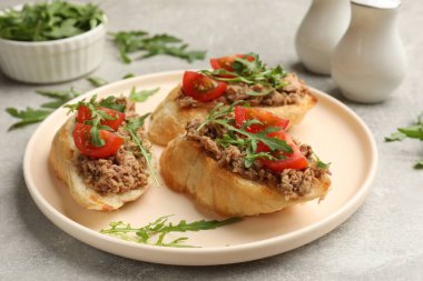 Ton balıklı lezzetli bruschettalar, domatesler ve roka gri masada, yakın plan.