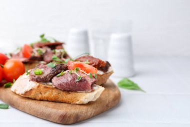 Beyaz fayanslı masada servis edilen biftekli nefis bruschetalar, yakın plan. Metin için boşluk