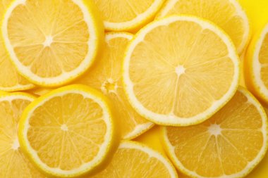 Sarı arka planda taze limon dilimleri, düz uzanmış.