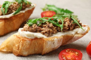 Ton balıklı lezzetli bruschettalar, domatesler ve roka gri masada, yakın plan.