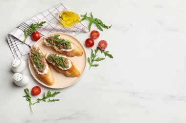 Lezzetli bruschettalar, ton balığı, domates, yağ ve roka, beyaz mermer masada, düz yerde. Metin için boşluk