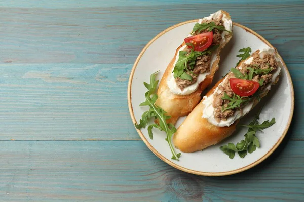 Açık mavi ahşap masada ton balıklı, krem peynirli ve domatesli nefis bruschettalar. Metin için boşluk