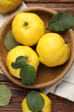 Tahta masadaki yapraklarla taze, olgun ayvalar.