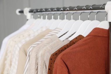 Gri duvarın yanında asılı farklı giysiler, yakın plan.