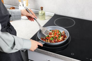 Kızartma tavasında taze sebze ve spatula karıştıran kadın, yakın plan.