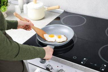 Mutfakta spatulalı sahanda yumurta yiyen bir kadın, yakın plan.