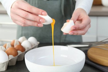 Mutfaktaki gri masada yumurta kıran kadın, yakın plan.