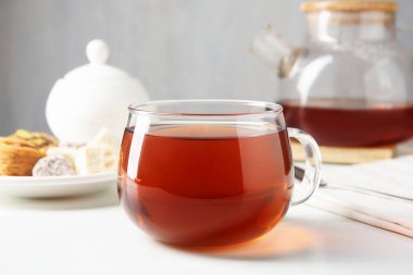 Beyaz masada cam bardakta çay, gri arka planda, yakın planda.