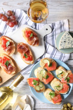 Somon, salatalık, limon, prosciutto ve beyaz ahşap masada şarap ile nefis bruschetalar.