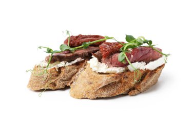 Biftek, krem peynir, güneşte kurutulmuş domates ve beyaz üzerine izole edilmiş mikro yeşillikler ile nefis bruschetalar.