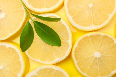 Taze limon dilimleri ve sarı arka planda yapraklar.