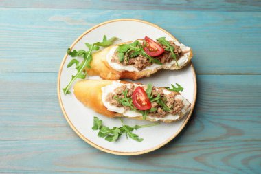 Açık mavi ahşap masada ton balıklı, krem peynirli ve domatesli nefis bruschettalar.