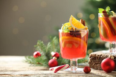 Gözlüklü, baharatlı ve Noel dekorlu kokteyl. Arka planda, bulanık ışıklar ve yazı için yer olan ahşap masa. Bokeh etkisi