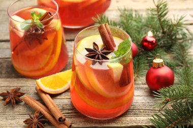 Lezzetli punç bardaklar, baharatlar ve Noel dekorları ahşap masada, yakın plan.