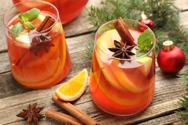 Lezzetli punç bardaklar, baharatlar ve Noel dekorları ahşap masada, yakın plan.