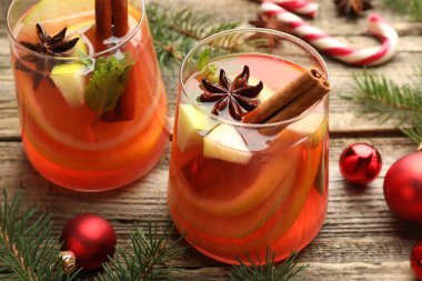 Lezzetli punç bardaklar, baharatlar ve Noel dekorları ahşap masada, yakın plan.