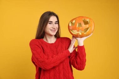 Mutlu Cadılar Bayramı. Sarı arka planda balkabağı kabağı oyulmuş bir kadın.